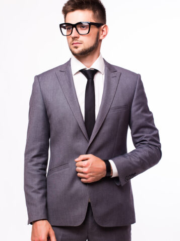 Attractive businessman standing in a blue suit and tie, wearing glasses. White background.