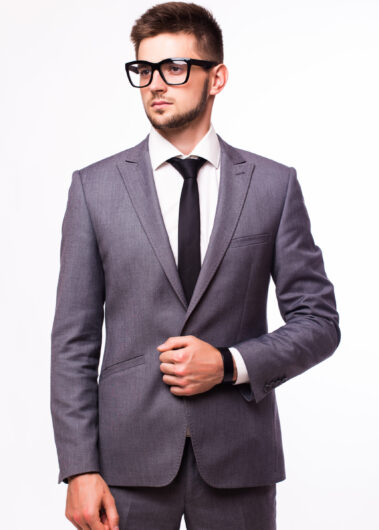 Attractive businessman standing in a blue suit and tie, wearing glasses. White background.